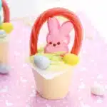 a vanilla pudding cup with edible grass, cadbury mini eggs, a peep, and a twizzler bent to look like a handle