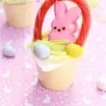 Easter Basket Pudding Cups - Cultivating Brilliant Minds a vanilla pudding cup with edible grass, cadbury mini eggs, a peep, and a twizzler bent to look like a handle