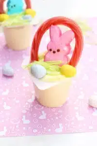 a vanilla pudding cup with edible grass, cadbury mini eggs, a peep, and a twizzler bent to look like a handle