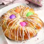 Italian Easter Bread Recipe - Cultivating Brilliant Minds a braided italian easter bread with colored eggs, glaze, and sprinkles