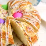 Italian Easter Bread Recipe - Cultivating Brilliant Minds a braided italian easter bread with colored eggs, glaze, and sprinkles