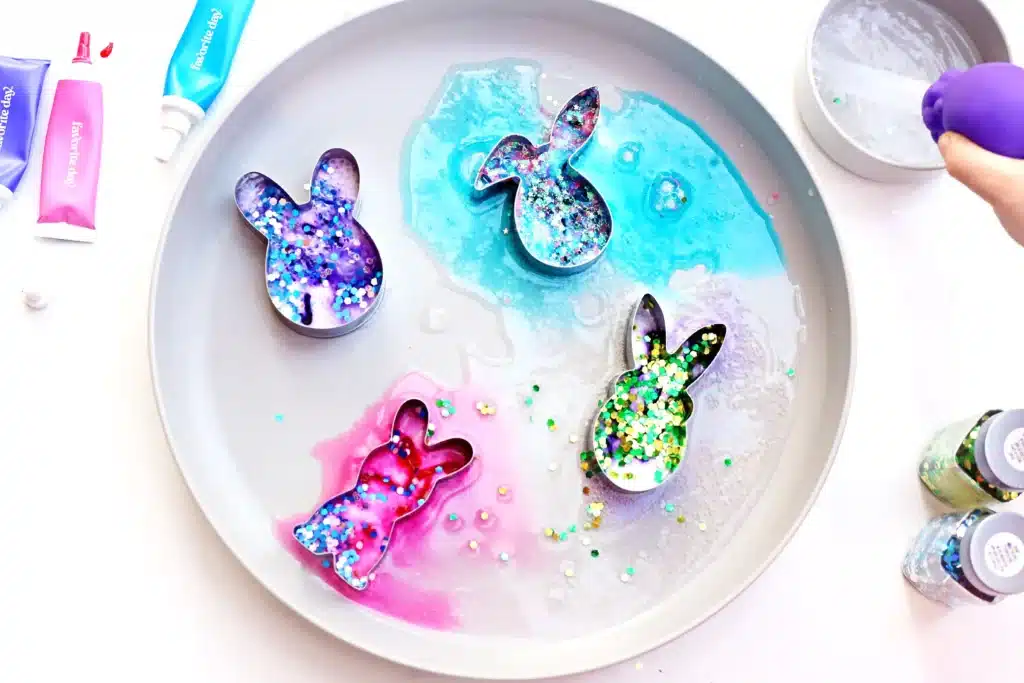Fizzy Bunny Experiment - Cultivating Brilliant Minds cookie cutters on a plate with baking soda, glitter, food coloring, and vinegar