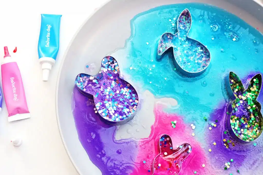 Fizzy Bunny Experiment - Cultivating Brilliant Minds cookie cutters on a plate with baking soda, glitter, food coloring, and vinegar in it to create a "volcano"