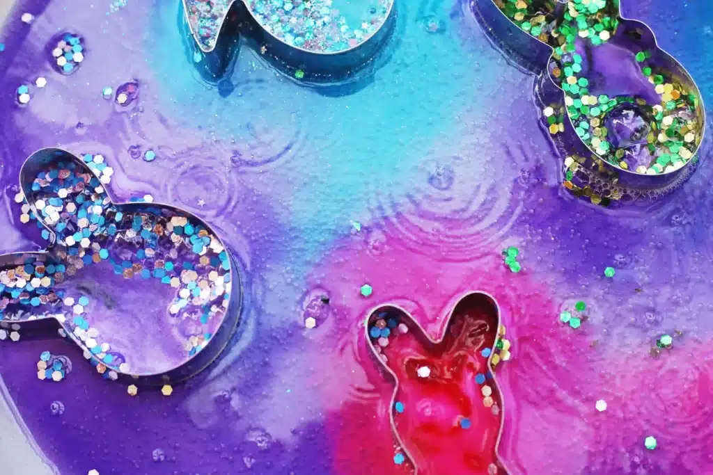 Fizzy Bunny Experiment - Cultivating Brilliant Minds cookie cutters on a plate with baking soda, glitter, food coloring, and vinegar in it to create a "volcano"