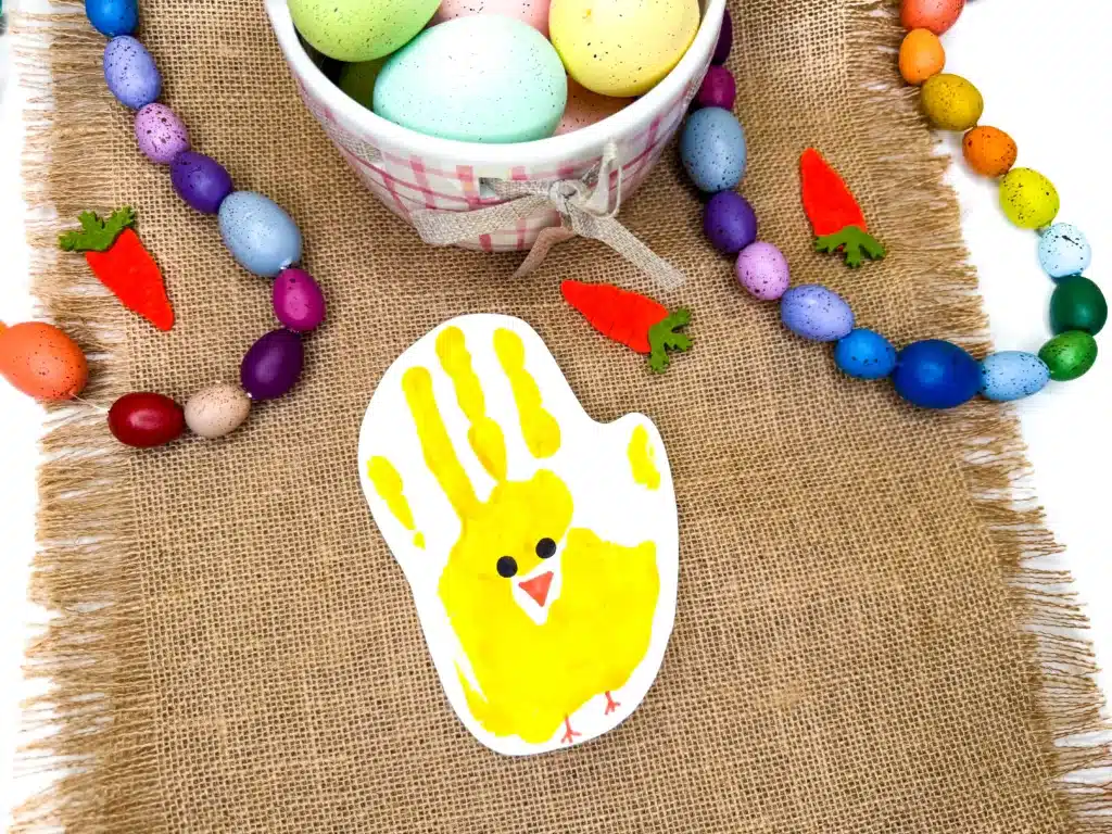 Chick Handprint Craft - Cultivating Brilliant Minds a piece of paper with a paint handprint that has eyes, a beak, and feet