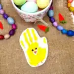 Chick Handprint Craft - Cultivating Brilliant Minds a piece of paper with a paint handprint that has eyes, a beak, and feet