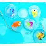an ice fishing sensory bin that has water and toy fish frozen in ice