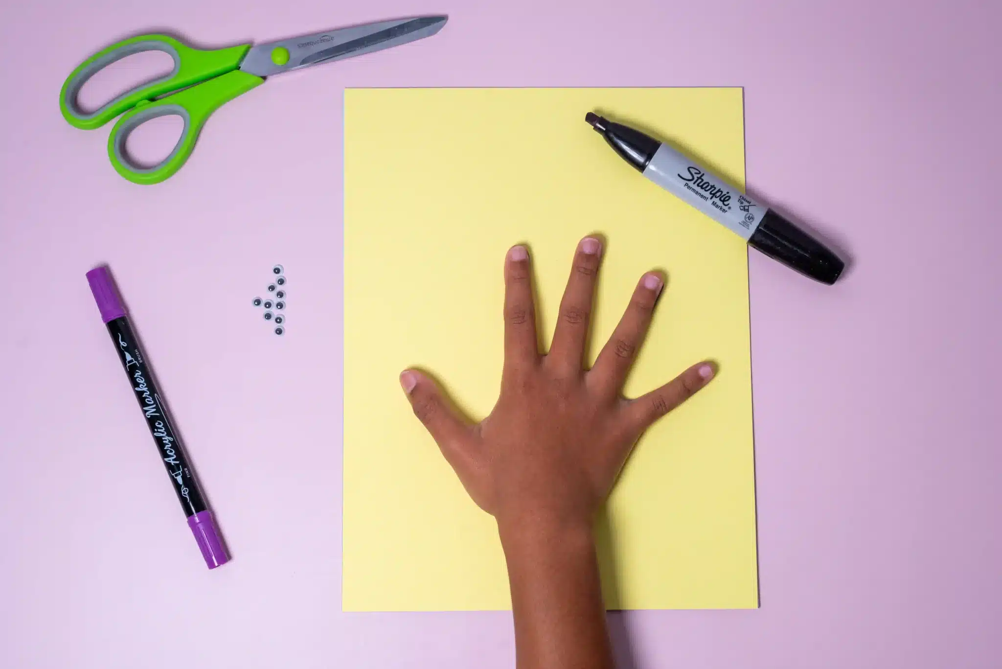 Bunny Handprint Craft - Cultivating Brilliant Minds a child's hand on yellow paper next to a sharpie