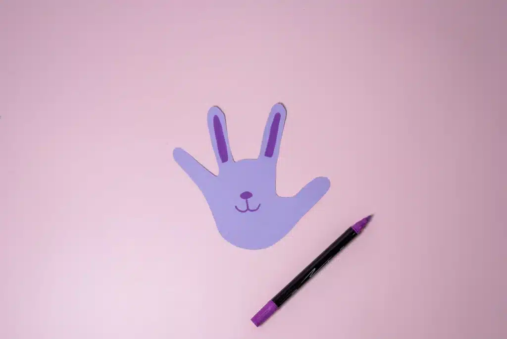 Bunny Handprint Craft - Cultivating Brilliant Minds a handprint cut out of colored paper decorated to look like a bunny
