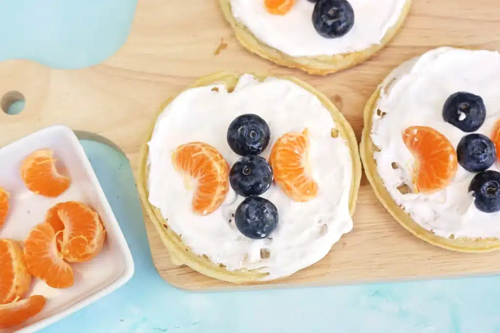 Butterfly Garden Waffles: A Spring Breakfast Idea For Kids - Cultivating Brilliant Minds waffles with whipped cream and blueberries and oranges arranged to look like a butterfly