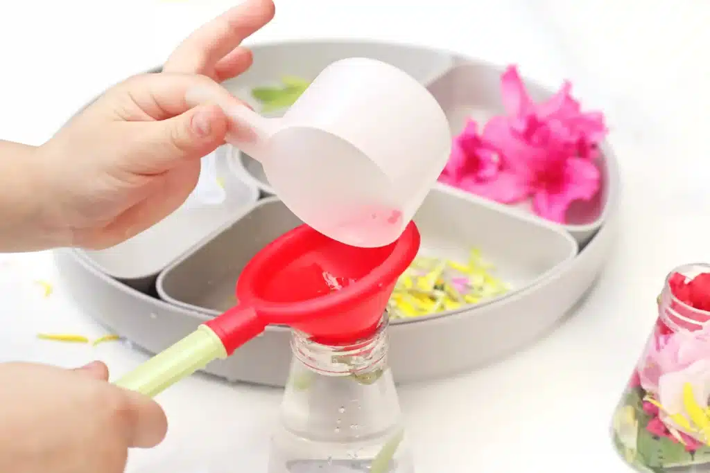 Spring Flowers Potion Sensory Activity - Cultivating Brilliant Minds a kid pouring water in a jar