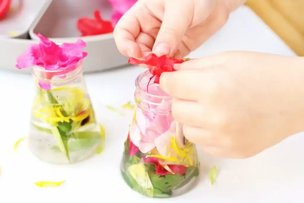 Spring Flowers Potion Sensory Activity - Cultivating Brilliant Minds a kid putting flowers in a jar with water