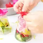 Spring Flowers Potion Sensory Activity - Cultivating Brilliant Minds a kid putting flowers in a jar with water