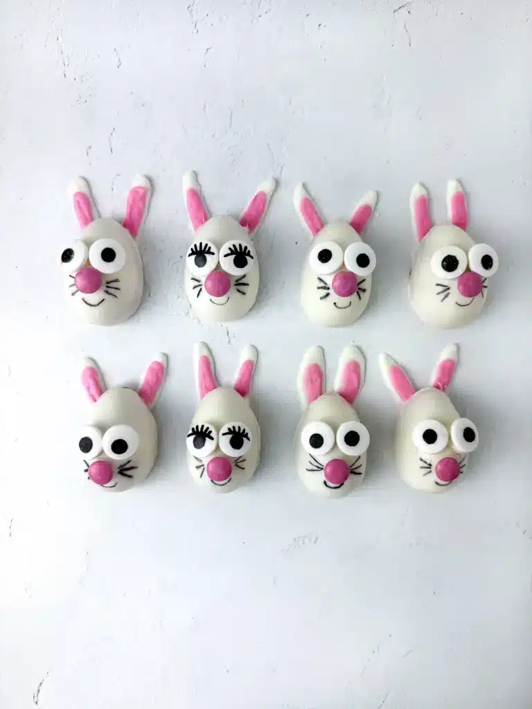 strawberry funfetti bunnies on a plate. They are white chocolate coated on a strawberry cupcake mixture, decorated to look like a bunny