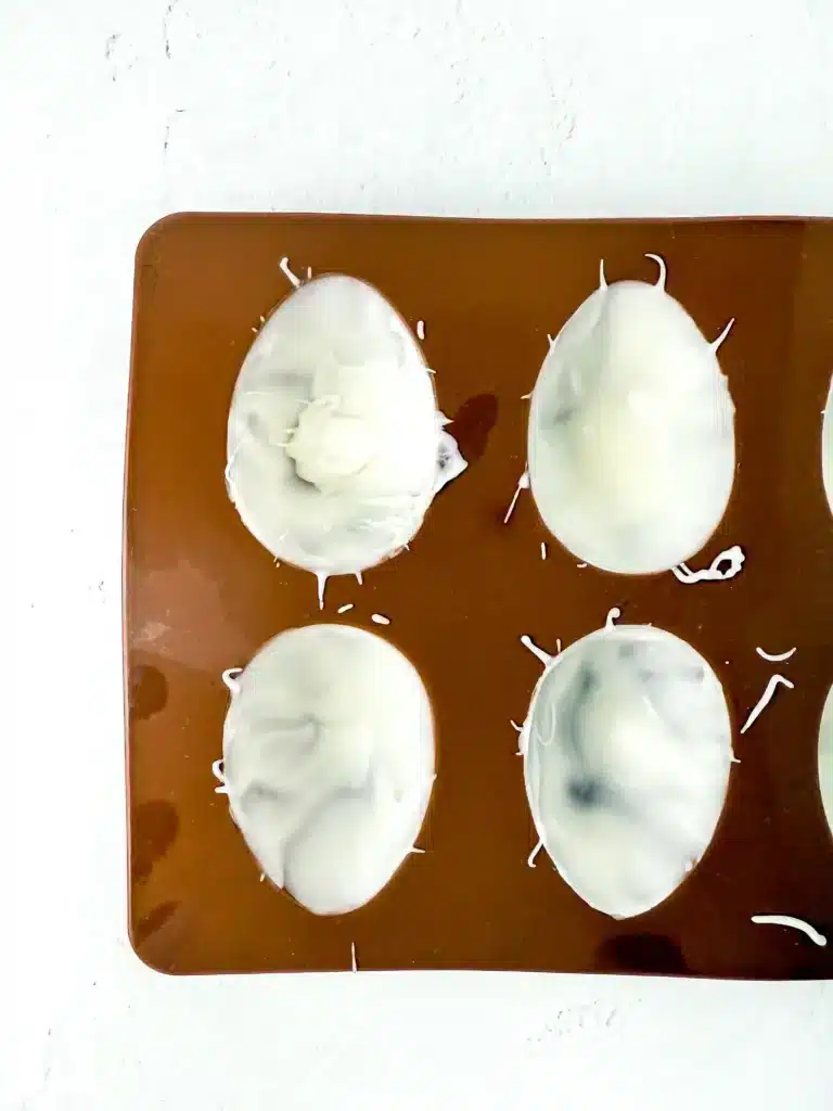 a mold shaped like eggs with white chocolate inside