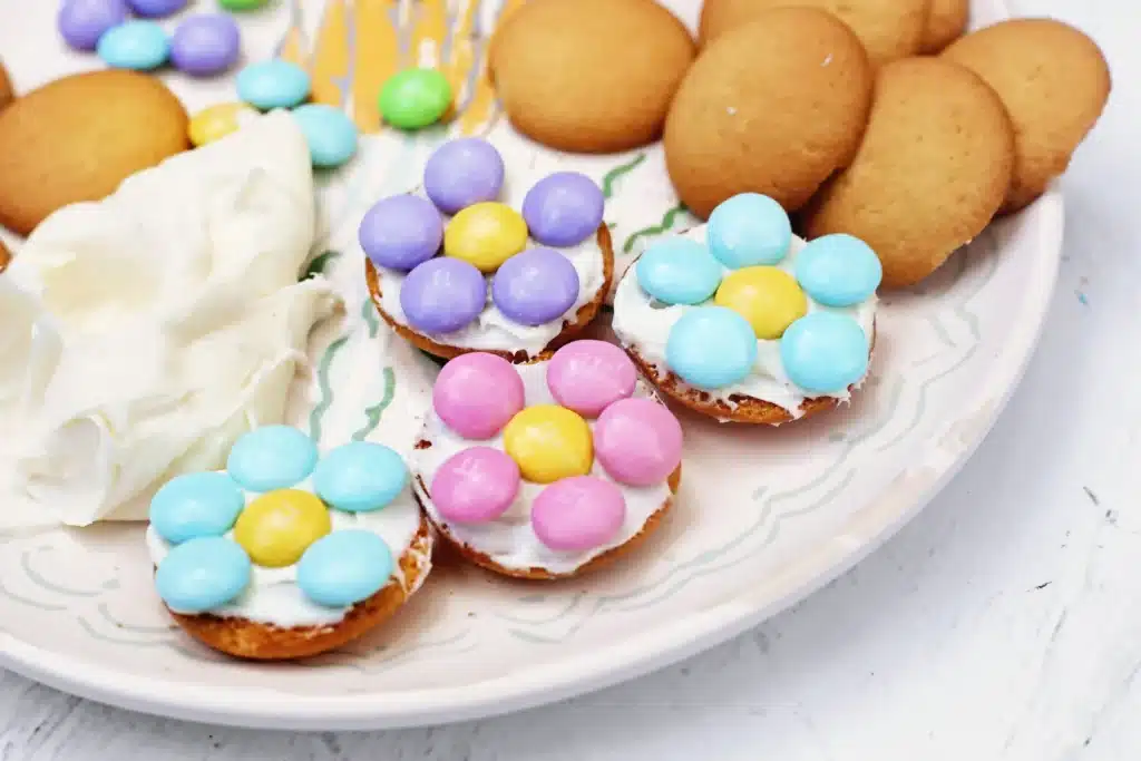 Vanilla Wafer Flower Cookies - Cultivating Brilliant Minds a vanilla wafer with icing and pastel m&ms in the shape of a flower
