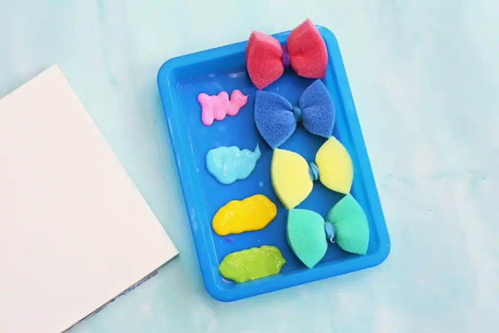 Sponge Painted Butterflies - Cultivating Brilliant Minds a tray with sponges that have rubber bands around the middle and different colored paint