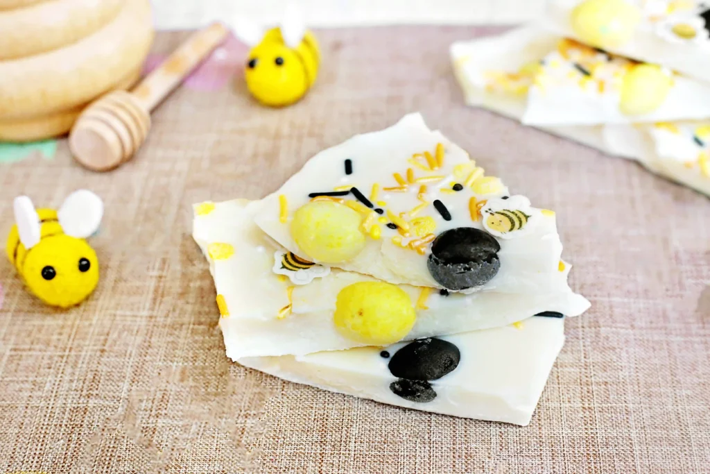 Bumble Bee Bark - Cultivating Brilliant Minds Bee-themed cookies with yellow and black decorations on a light wooden surface, plus a small bee figurine nearby.