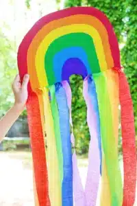 a piece of cardboard cut and painted like a rainbow with streamers on the bottom