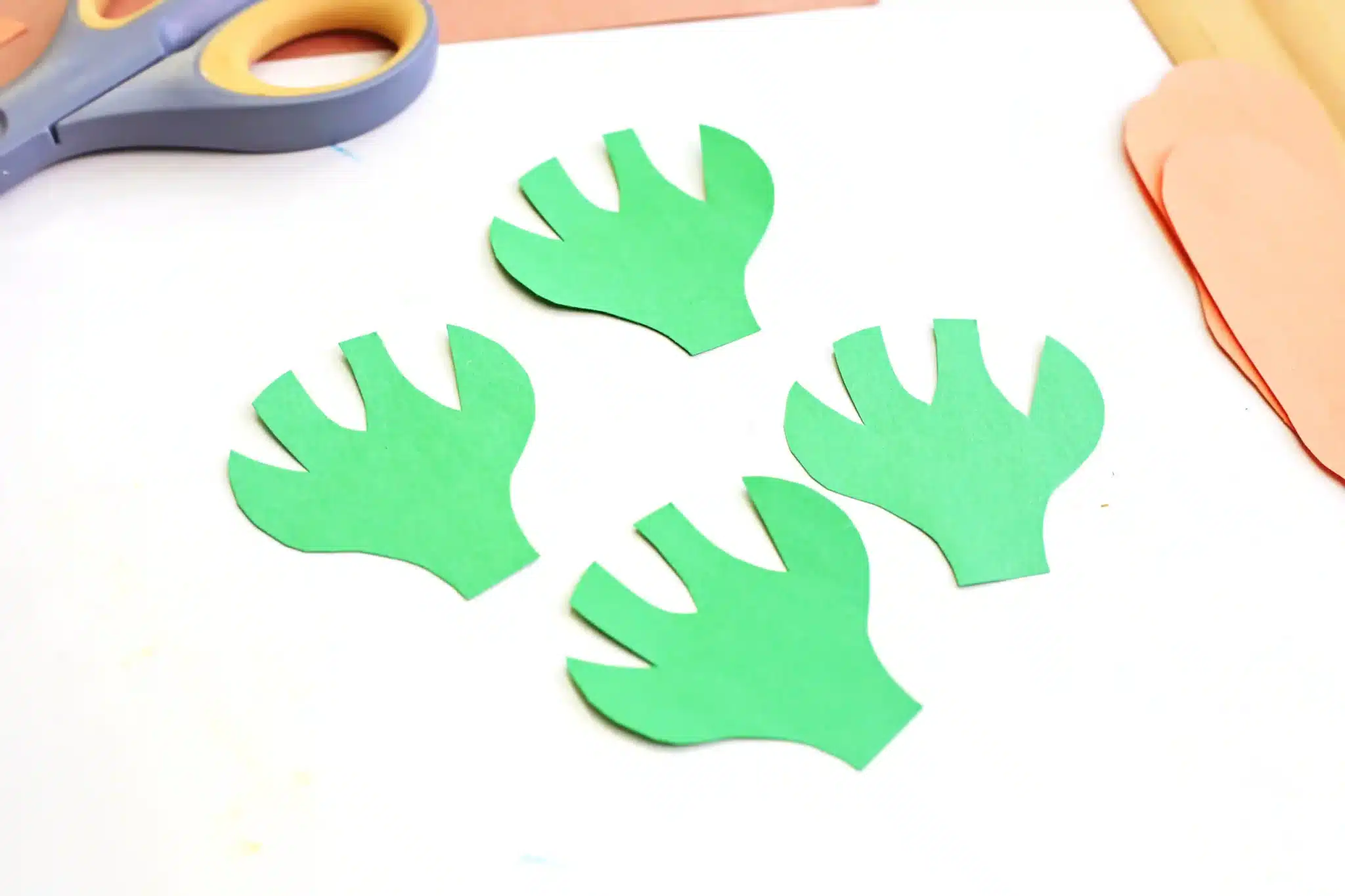 Carrot Garden Paper Plate Craft - Cultivating Brilliant Minds green construction paper cut to look like the tops of carrots