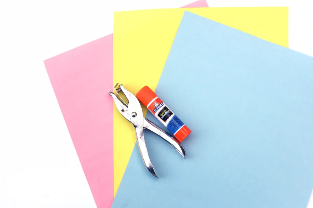 Letter D Craft - Cultivating Brilliant Minds supplies for the letter d craft : pink yellow and blue paper, hole puncher, and glue