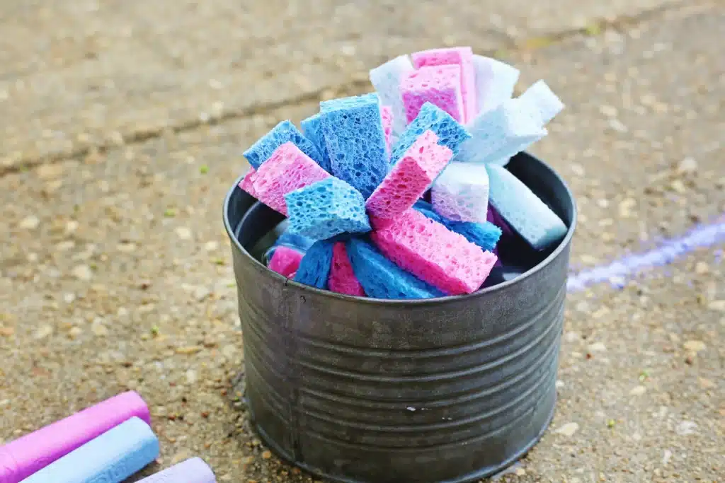 DIY Sponge Toss - Cultivating Brilliant Minds Metal tub filled with pink, blue, and purple kitchen sponges outdoors on a gravel surface