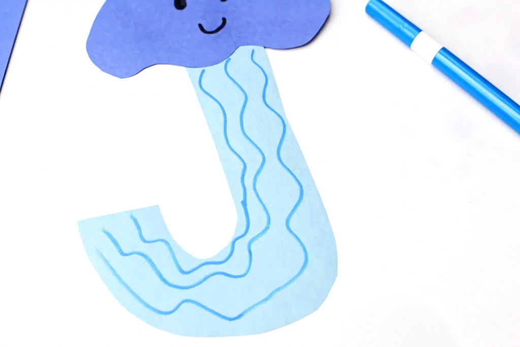 Letter J Jellyfish Craft - Cultivating Brilliant Minds blue construction paper cut out to look like a jellyfish whit blue squiggles down the middle
