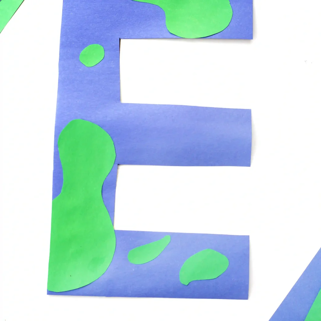Blue paper cutout in the shape of the letter E with green irregular patches on a white background, in a collage art style.
