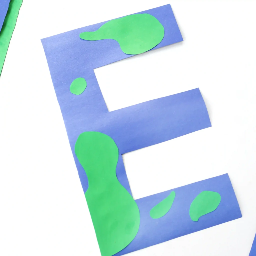 a blue letter e craft with green blobs to look like earth