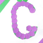 a letter g craft for preschoolers of a construction paper g with purple circles to represent grapes