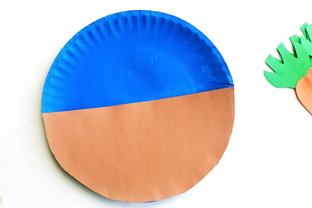 Carrot Garden Paper Plate Craft - Cultivating Brilliant Minds a paper plate painted blue with a brown semi-circle piece of construction paper glued to it