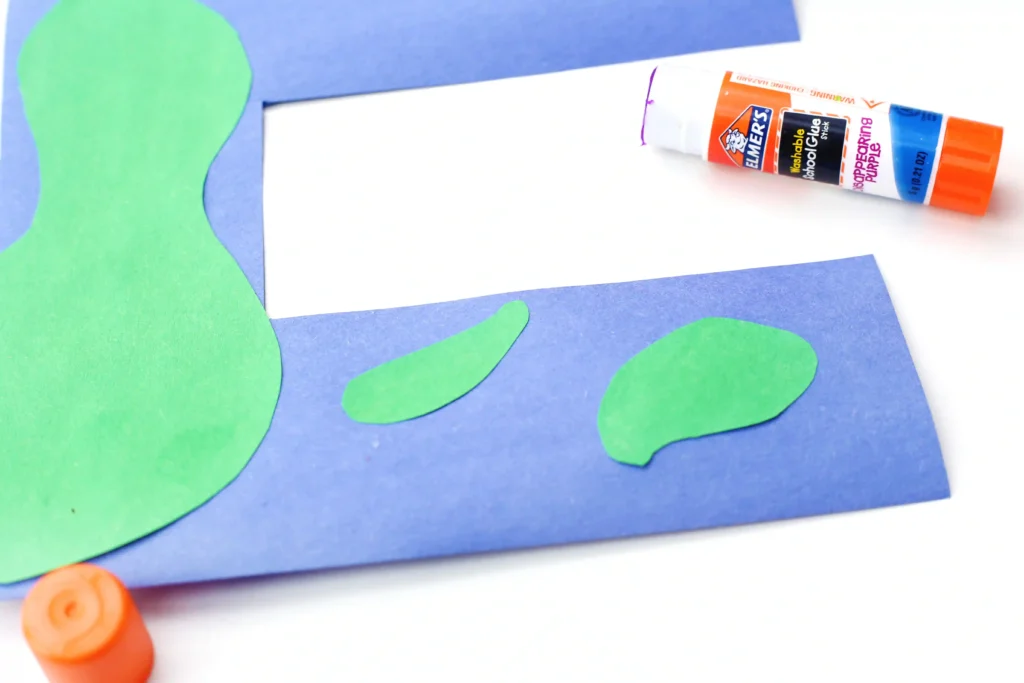 Letter E Earth Craft - Cultivating Brilliant Minds Blue paper cutout in the shape of the letter E with green irregular patches on a white background, in a collage art style.