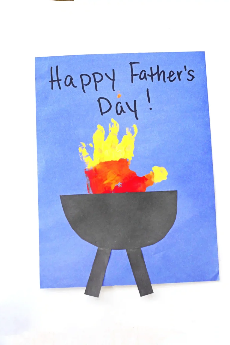 a yellow, orange, and red handprint with a construction paper grill on blue paper that reads" happy father's day!"