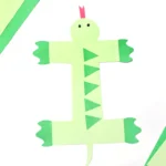 a letter i cut out of green construction paper and decorated to look like an iguana