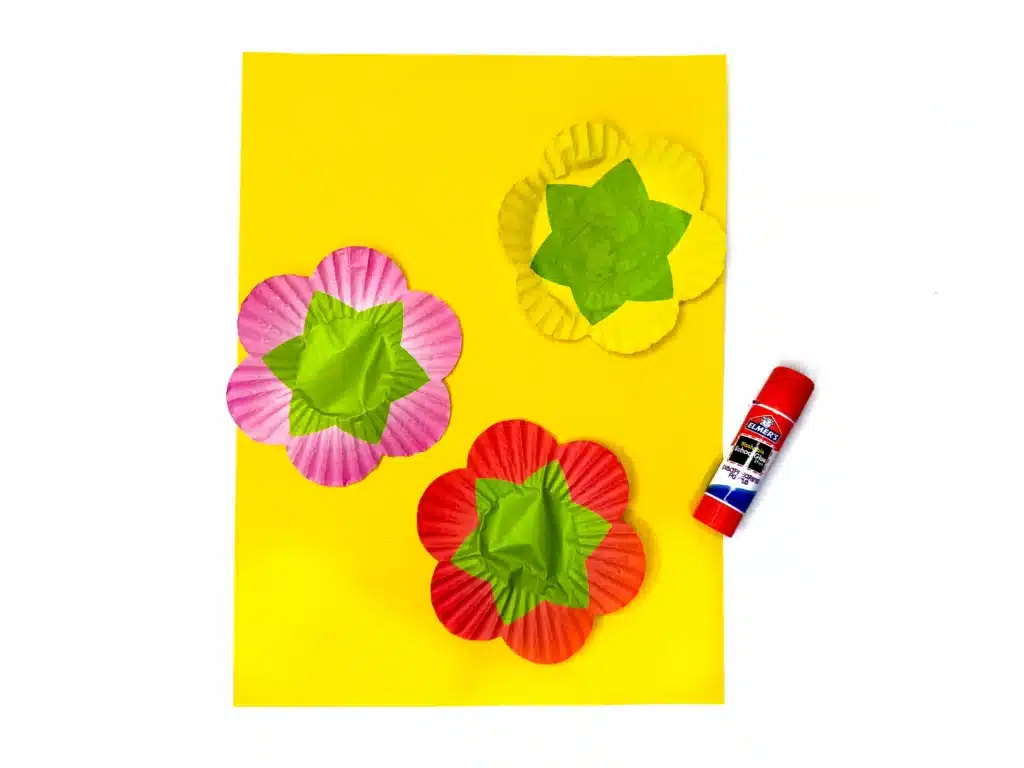 Cupcake Liner Flower Craft - Cultivating Brilliant Minds cupcake liners spread out flat on yellow construction paper for this mother's day gift