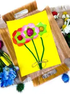 a cupcake liner flower craft that uses cupcake liners and pom poms as the flowers and pipe cleaners for the stems