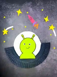 a paper plate cut and painted to look like a UFO with an alien inside