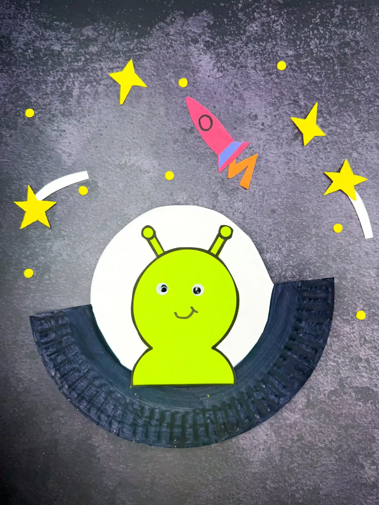 a paper plate cut and painted to look like a UFO with an alien inside