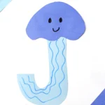 a letter j craft cut out of blue construction paper to look like a jellyfish