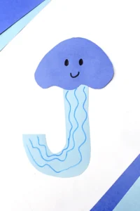 a letter j craft cut out of blue construction paper to look like a jellyfish