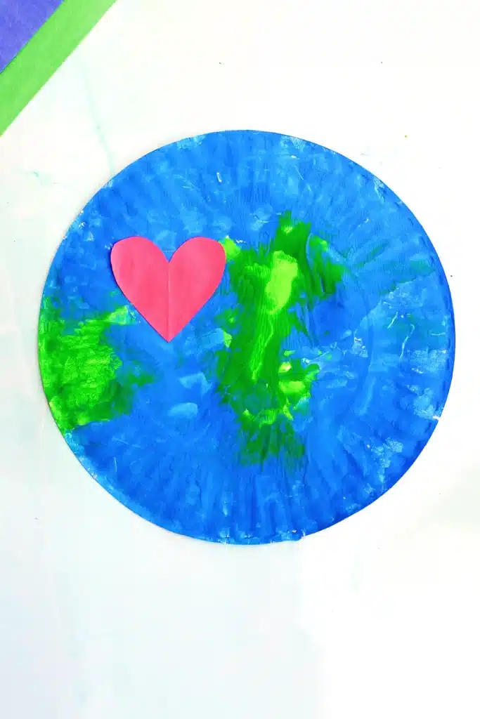 No-Mess Earth Day Painting - Cultivating Brilliant Minds a paper plate painted with green and blue paint to look like an Earth with a red construction paper heart