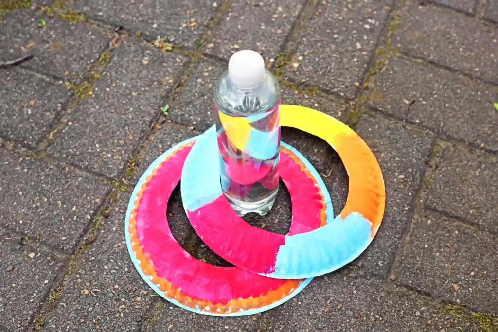 Paper Plate Ring Toss Game - Cultivating Brilliant Minds a paper plate with the center cut out around a water bottle to make a paper plate ring toss game
