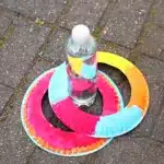 a paper plate with the center cut out around a water bottle to make a paper plate ring toss game