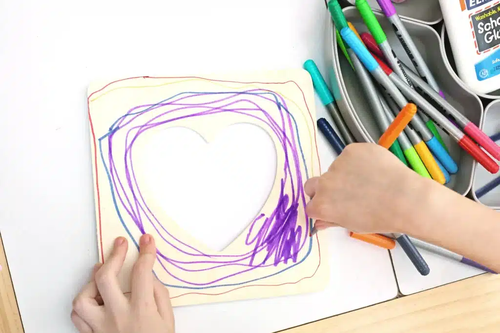 Picture Frame Decorating Tray - Cultivating Brilliant Minds a kid coloring a wooden picture frame with markers