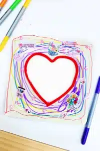 a square wooden picture frame with a heart in the middle decorated with stickers and markers