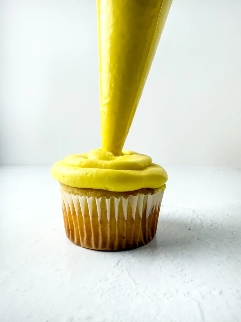 Pineapple Cupcakes - Cultivating Brilliant Minds Cupcake with bright yellow frosting being piped on top in a swirl shape