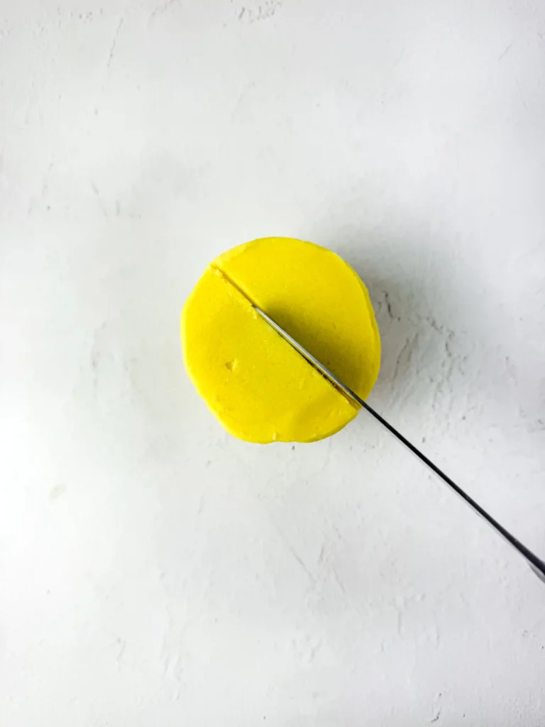 Pineapple Cupcakes - Cultivating Brilliant Minds a knife adding a slight indent on a cupcake with yellow icing