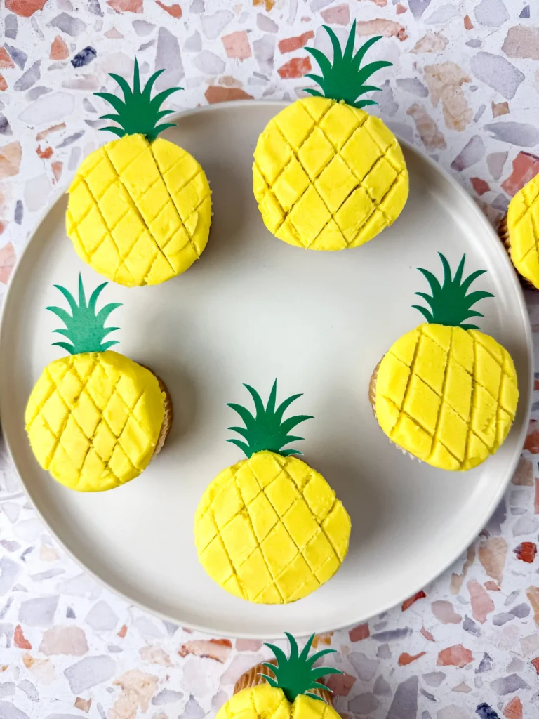 Pineapple Cupcakes - Cultivating Brilliant Minds vanilla cupcakes with yellow icing and a green pineapple cake topper