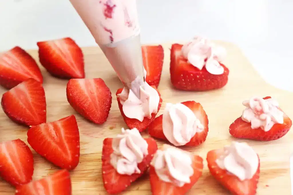 Deviled Strawberries - Cultivating Brilliant Minds piping the cream cheese filling on the strawberries