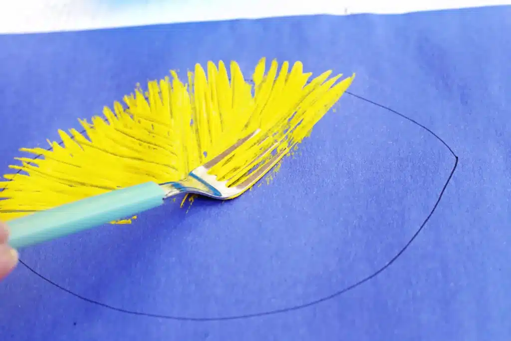 Fork Painted Bee - Cultivating Brilliant Minds A Fork spreading bright yellow paint on a blue surface, tracing a circle with a black guide line nearby.